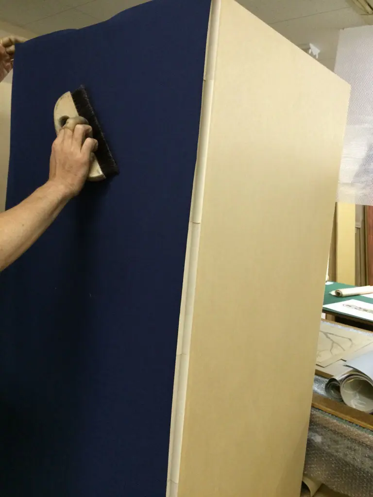 職人が屏風の生地を刷毛で仕上げている制作工程